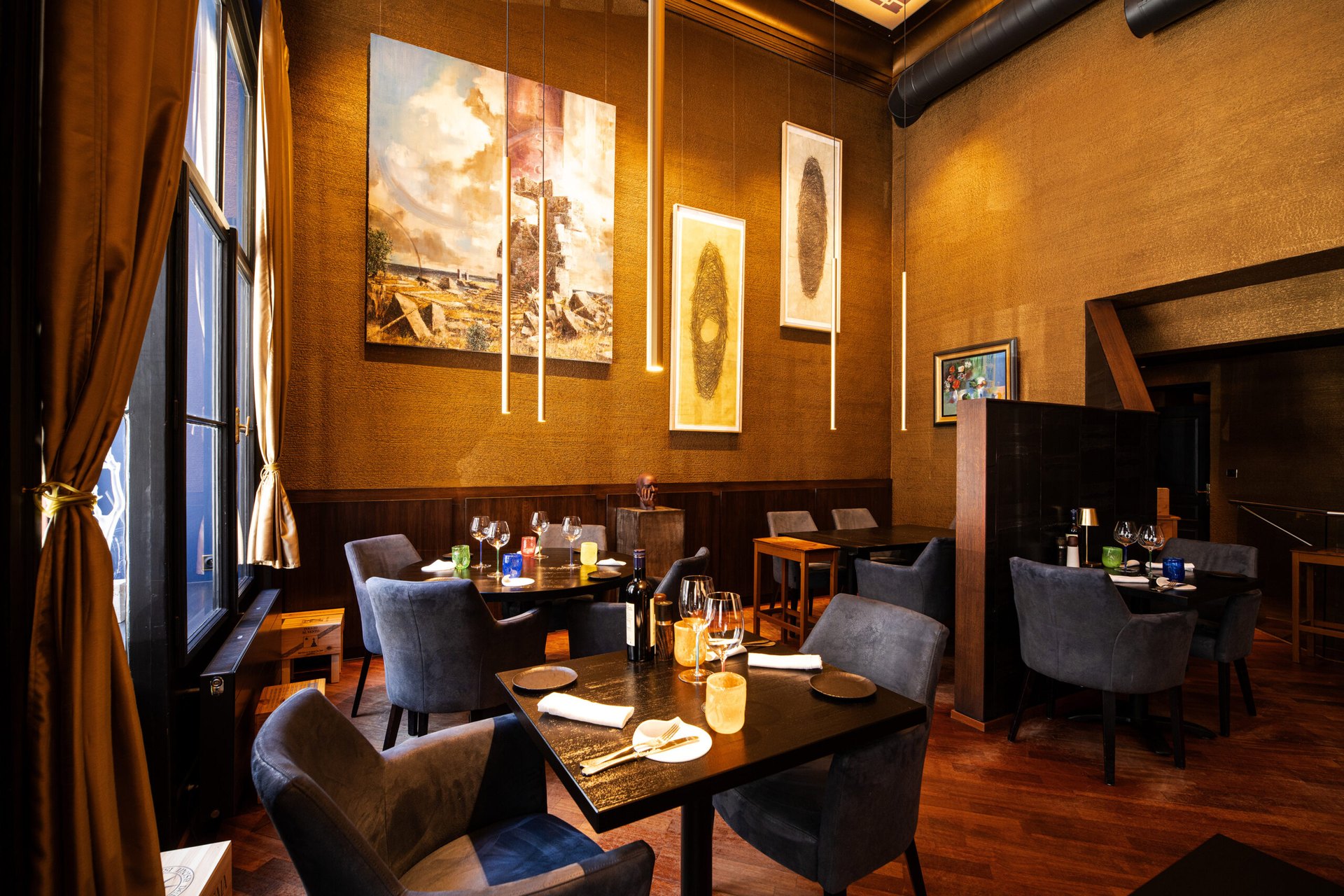 The dining room of Casa De Carli, with dark tables, gold walls and large paintings