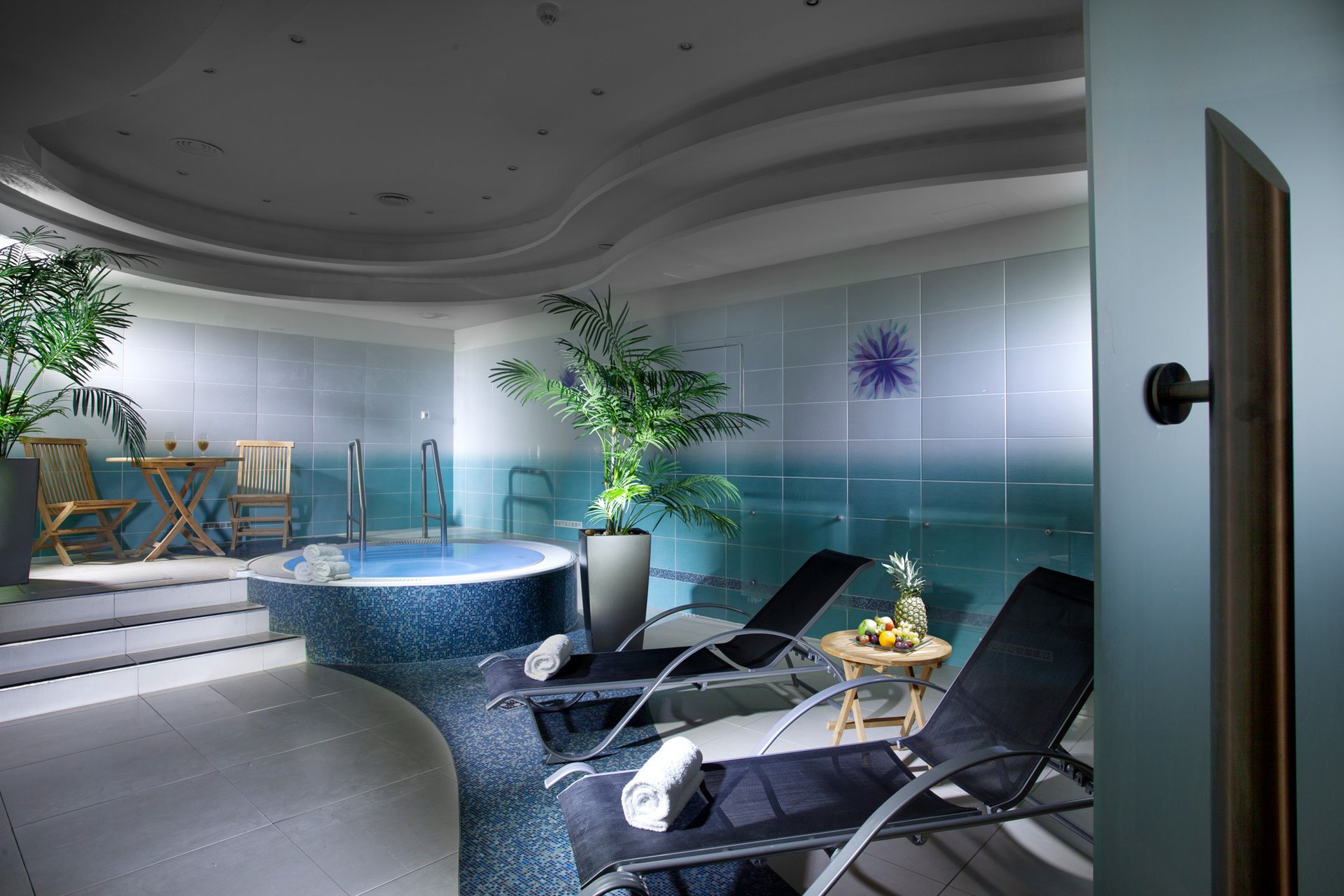 The spa of the Hotel Paris: a whirlpool, palms and loungers under a curved ceiling